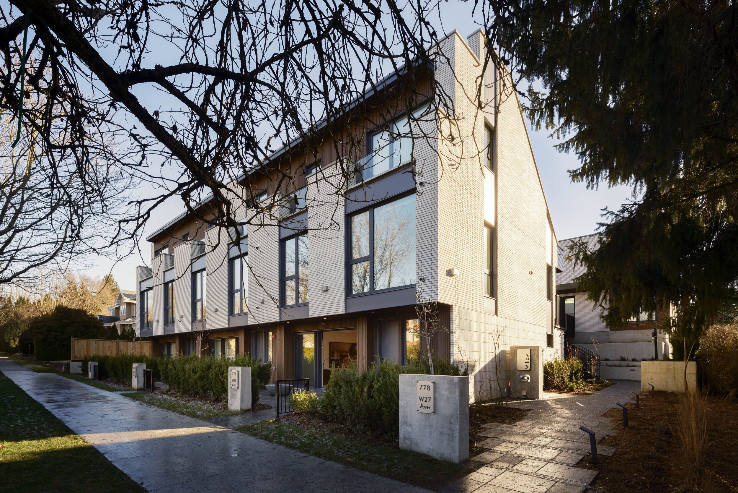 Modern townhouse complex with large windows and brick exterior, surrounded by leafless trees and landscaped pathways, located at 778 W27 Ave.