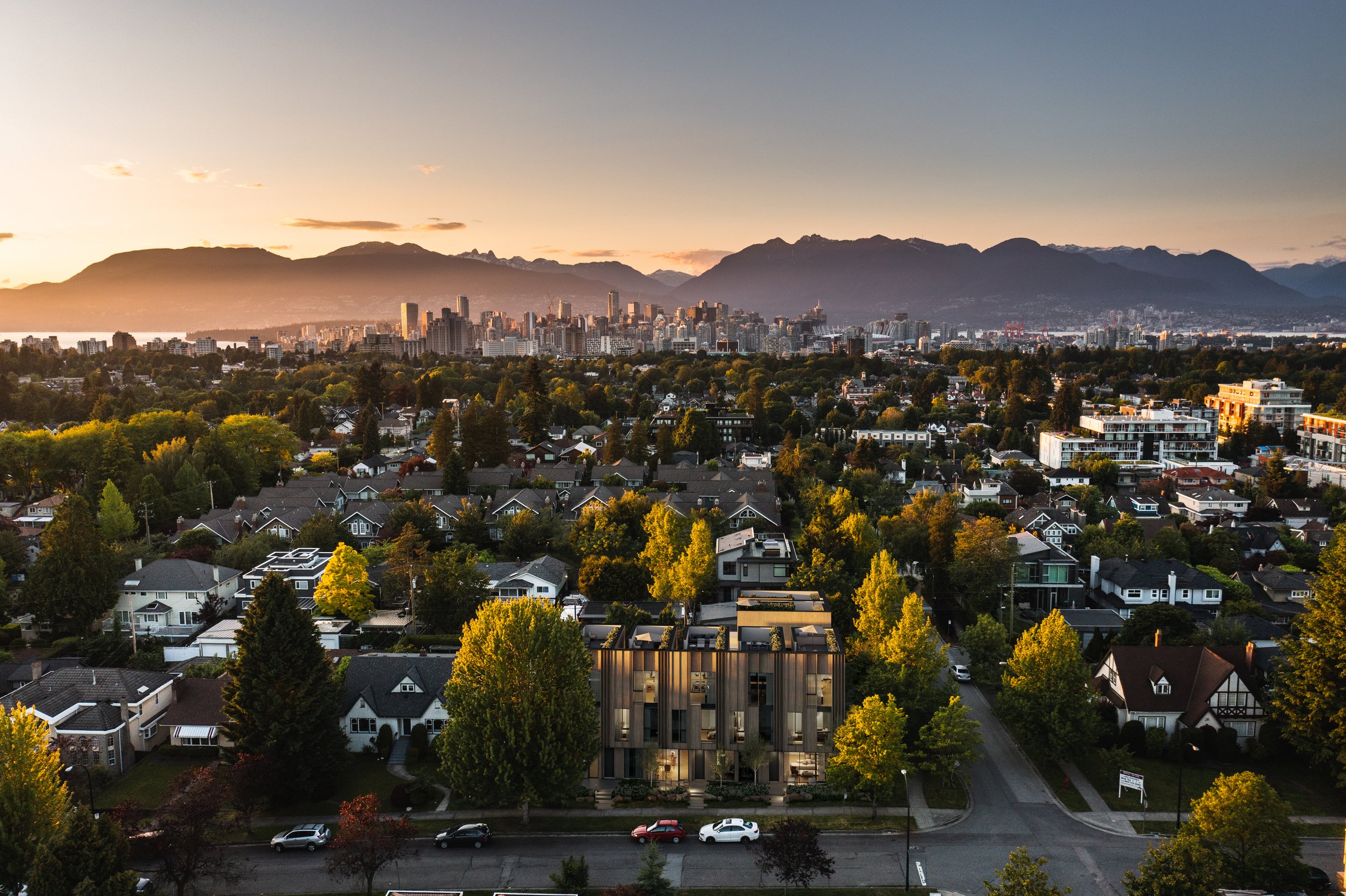 Aerial view of a Vancouver westside neighborhood with a Vancouver downtown city skyline and north shore mountain range at sunset.