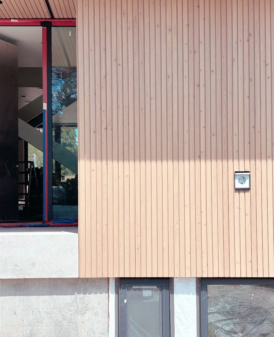 Exterior wall with vertical wood slats, large window, and concrete base