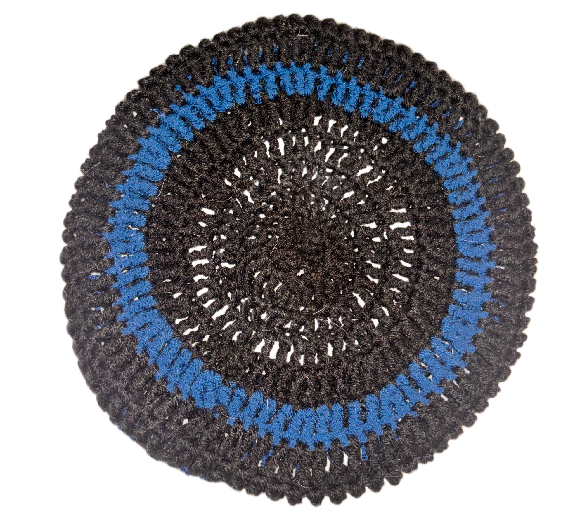 Close-up of a circular black, blue, and black crocheted hat or item with intricate pattern.