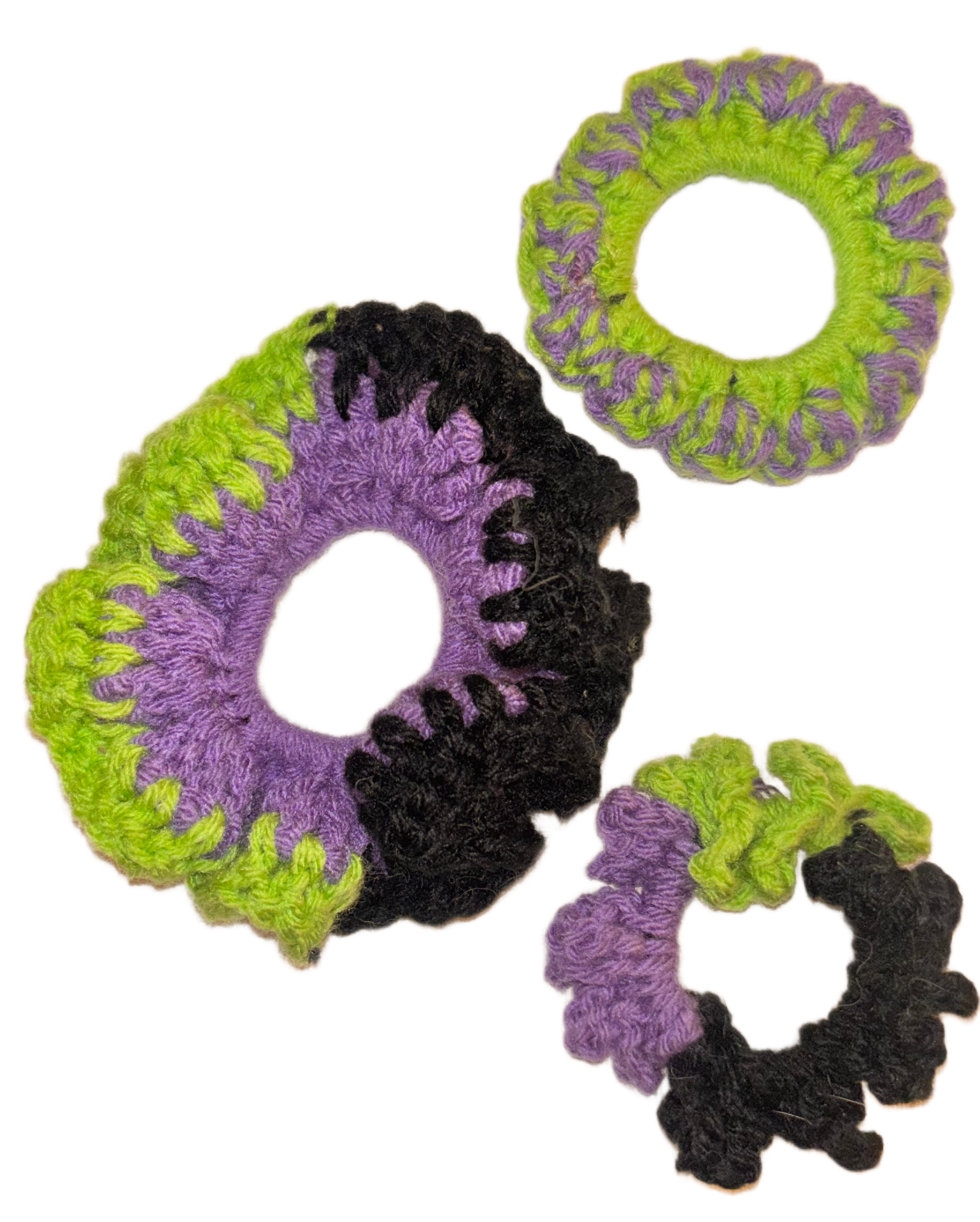 Colorful crocheted hair ties with purple, black, and green yarn, arranged in a group on a white background.
