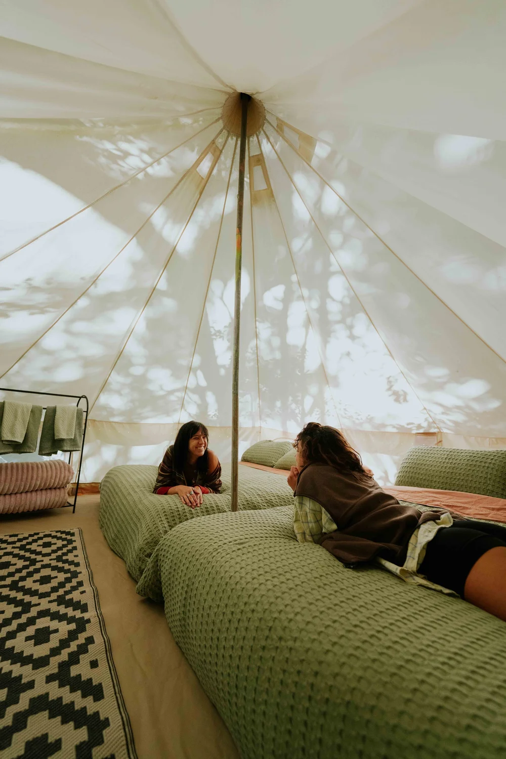 Two guests laughing together inside a bell tent