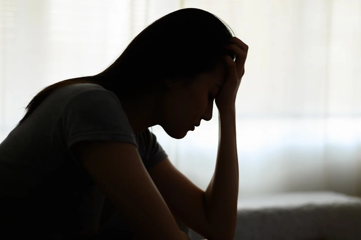 Silhouette of a sad woman with her hand on her head