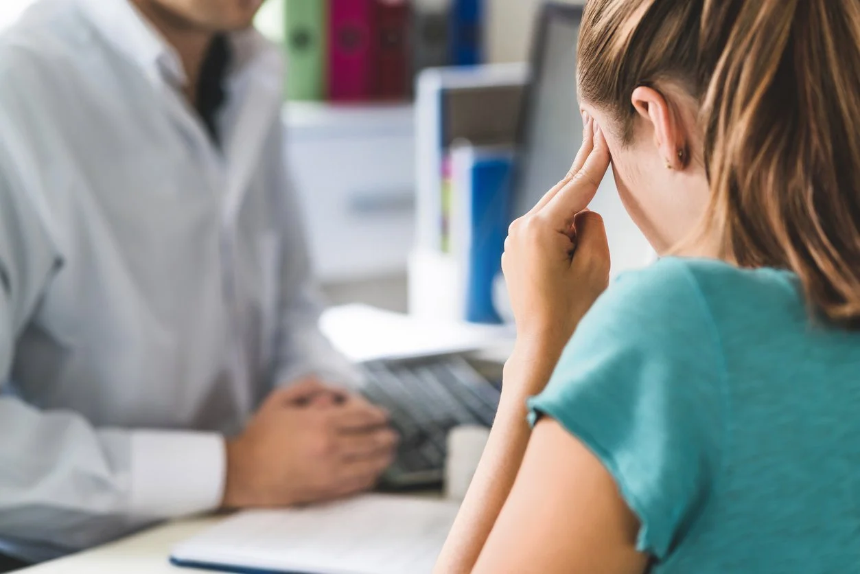 oung patient in pain holding head with hands.