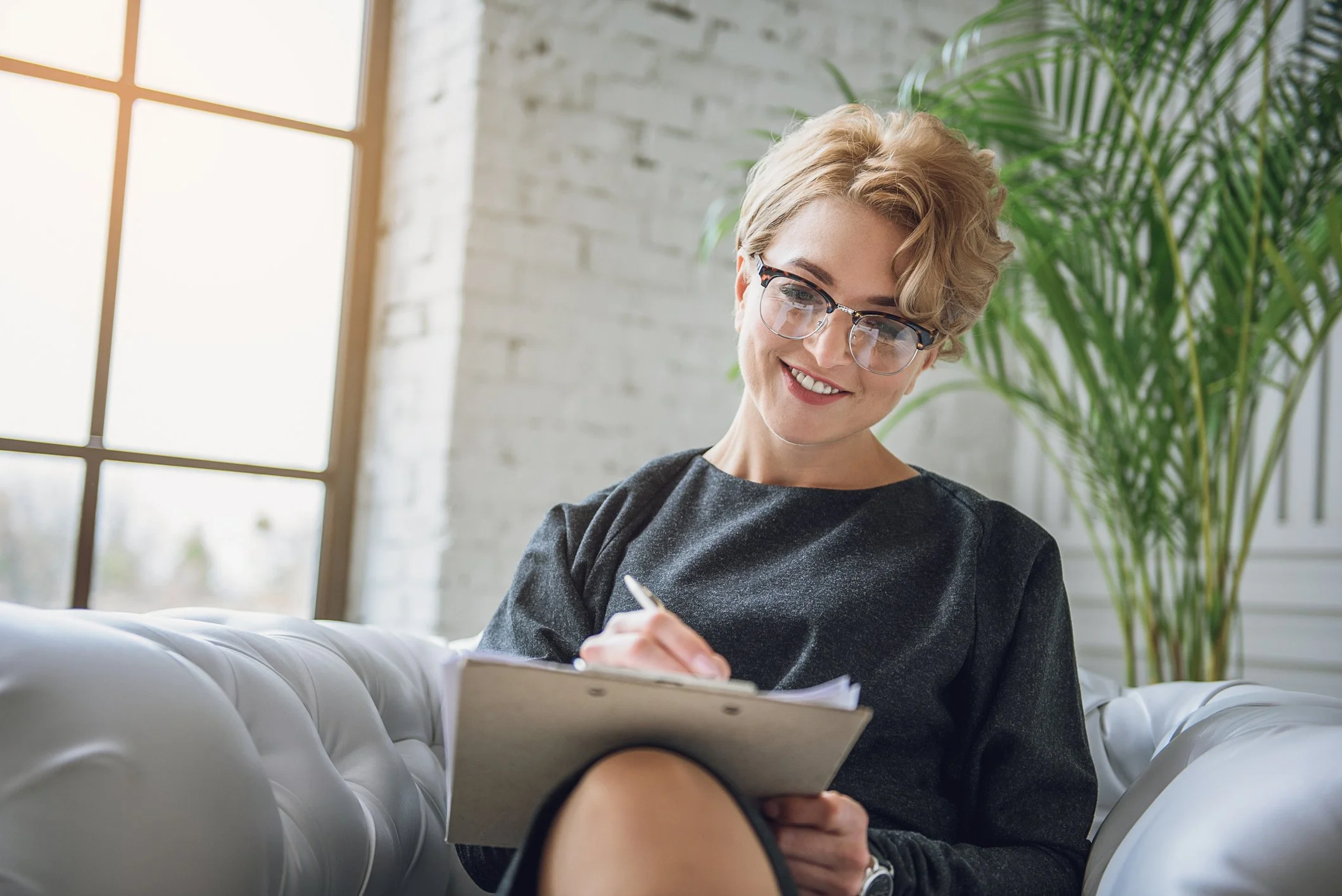 a woman smiling while writing on a notepad