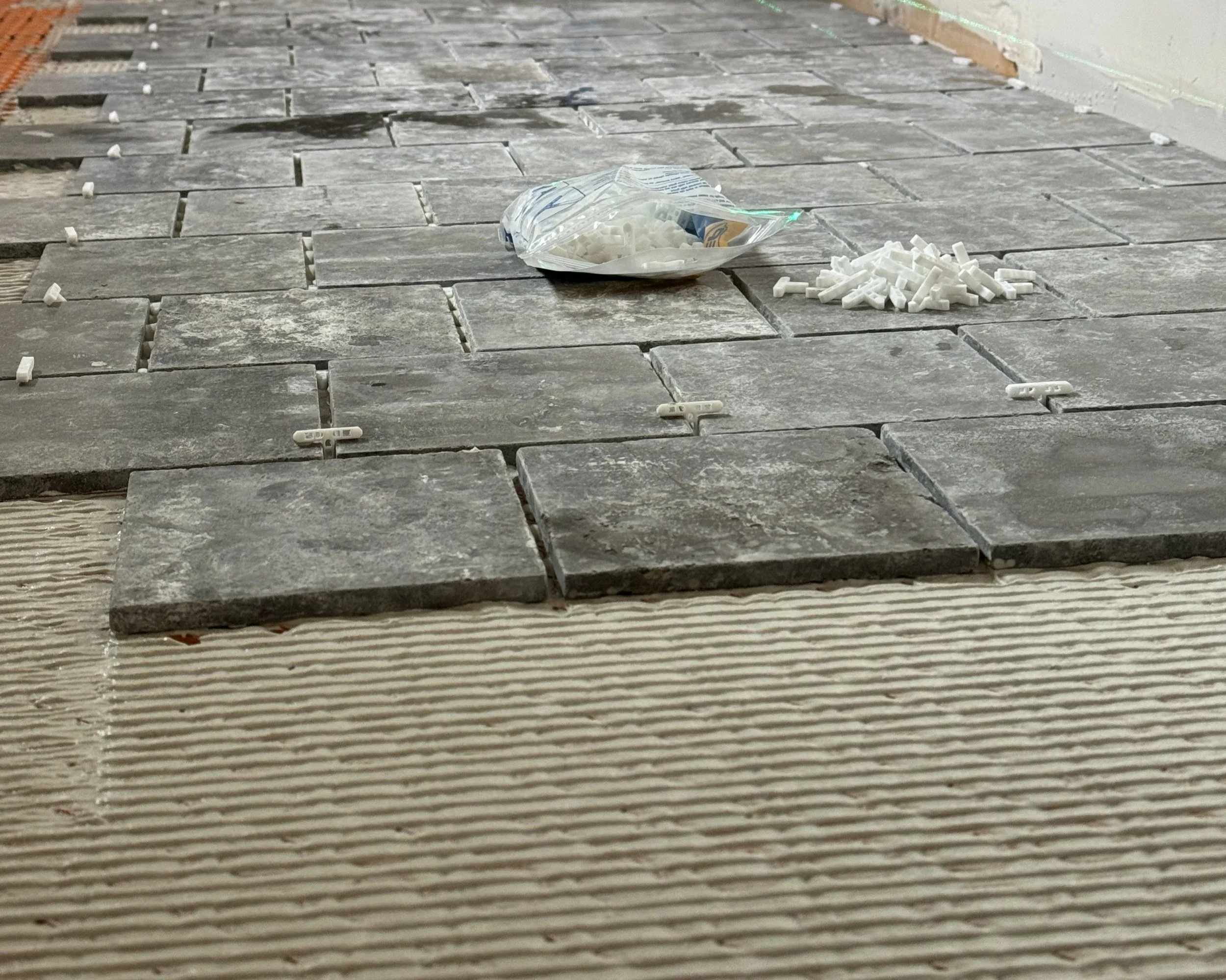 Floor tiles being installed with spacers and adhesive