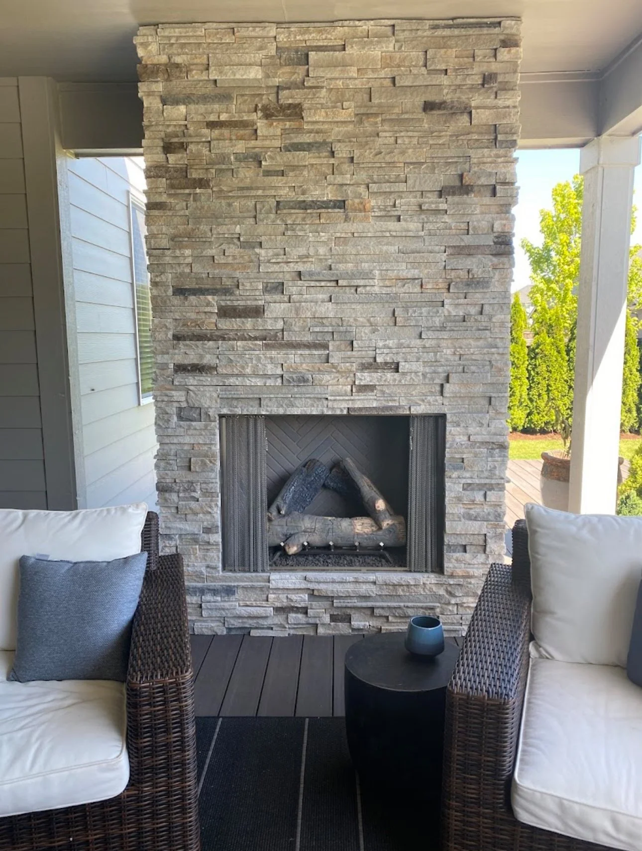 Outdoor stone fireplace full wrap around, on a covered patio.