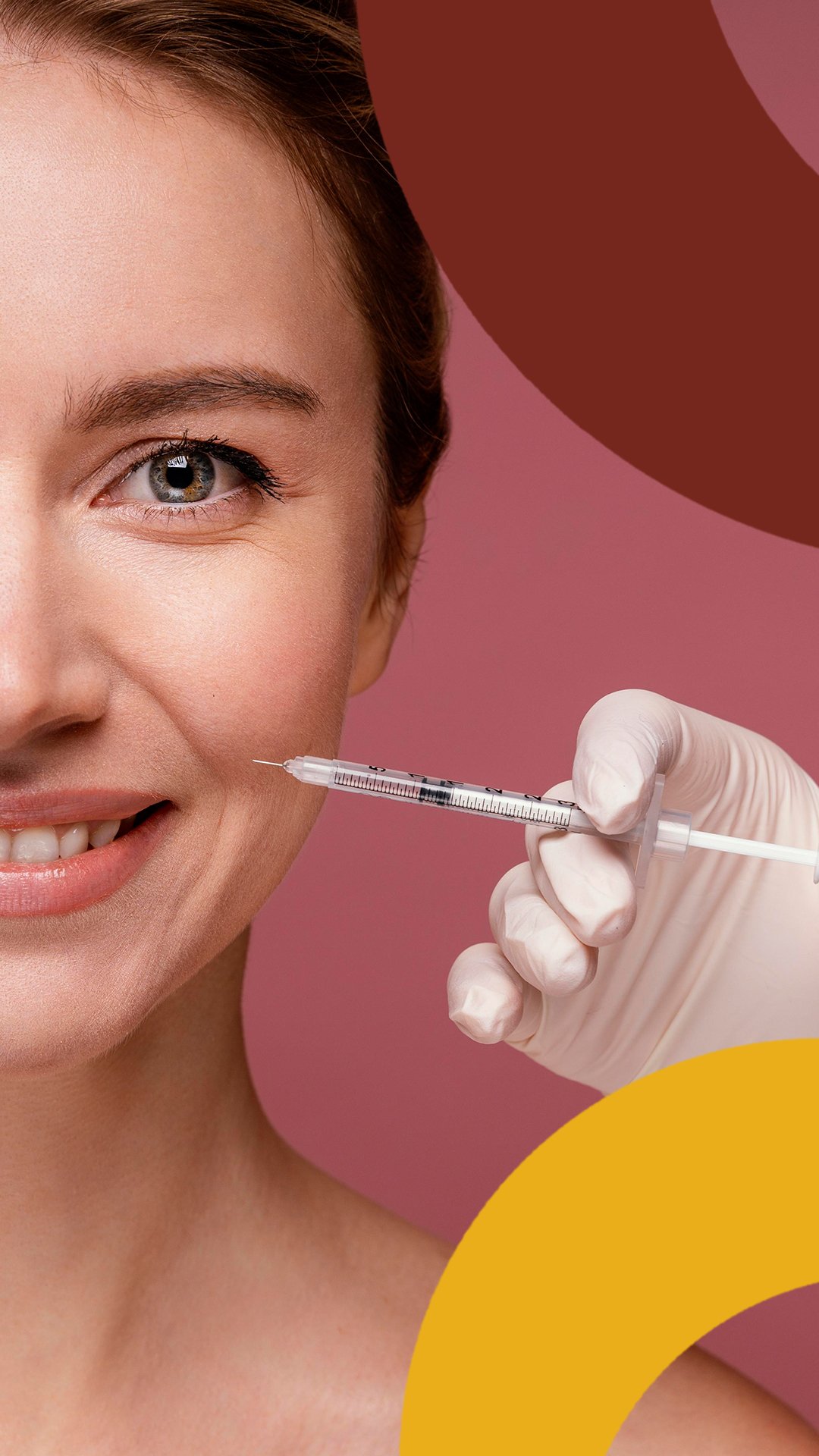 Close-up of a smiling woman receiving a cosmetic injection in her cheek from a healthcare professional wearing gloves, against a pink background.
