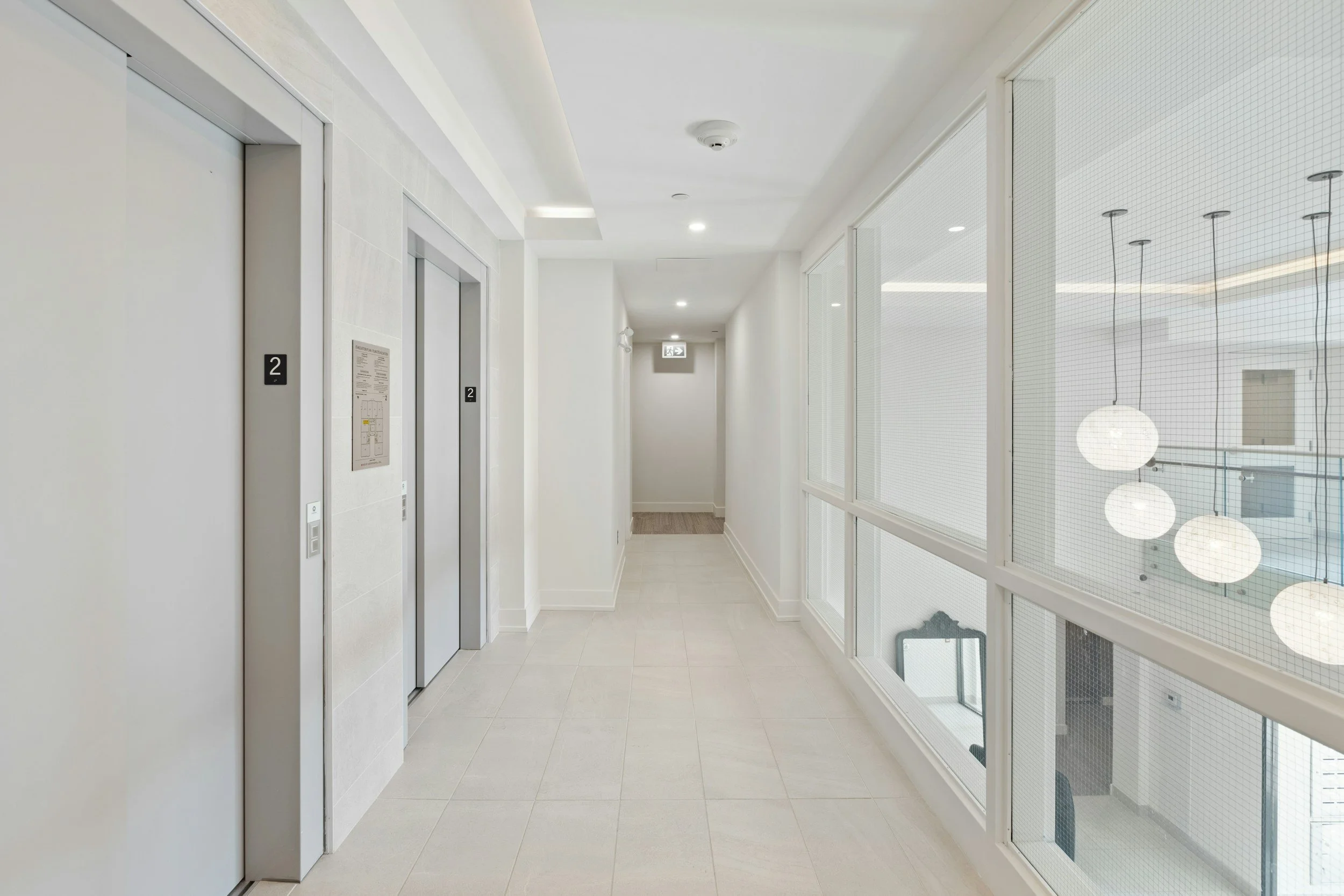 Clean white hallway featuring elevators of a cleaned apartment building