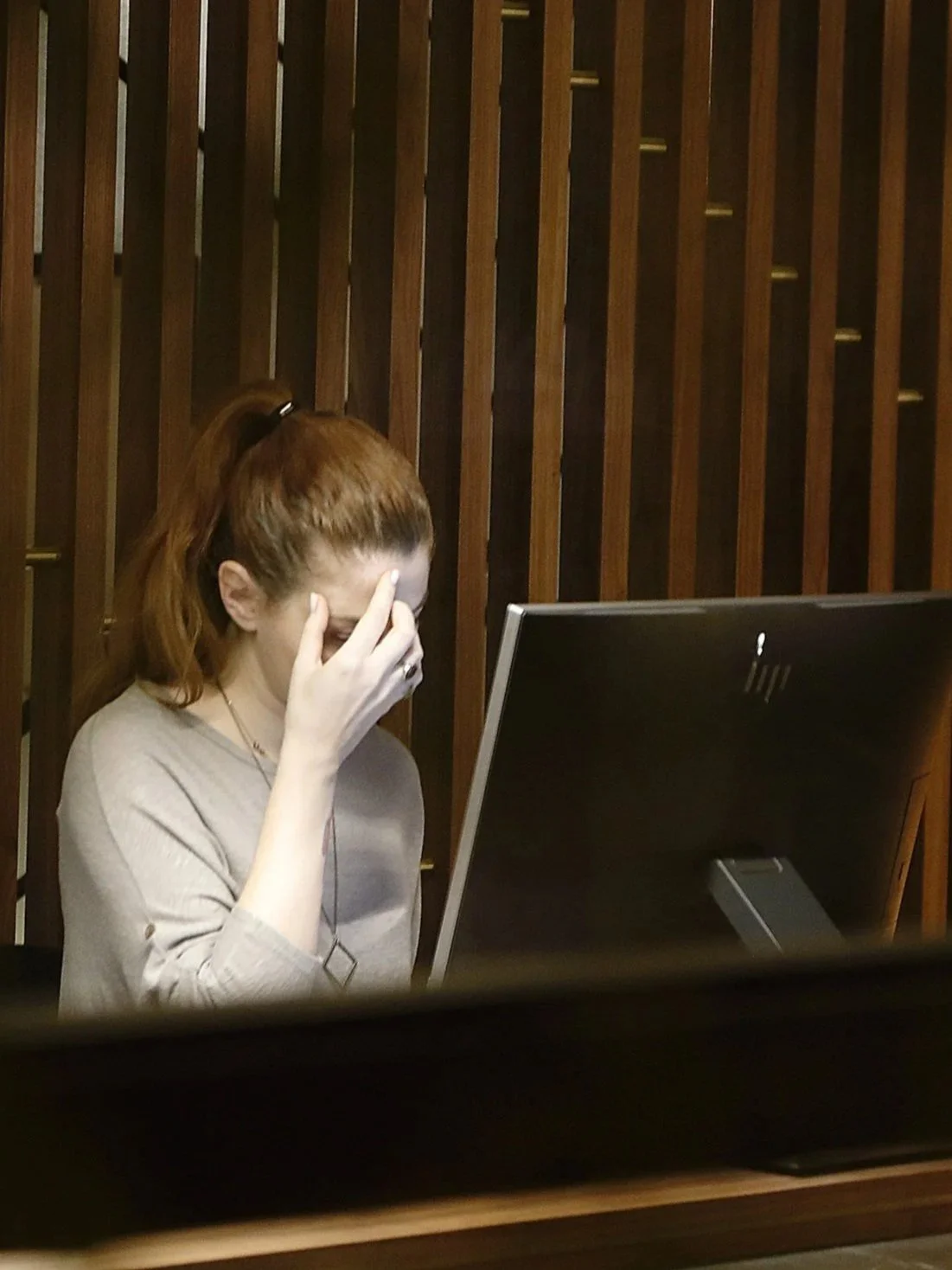 person sitting at computer holding their head