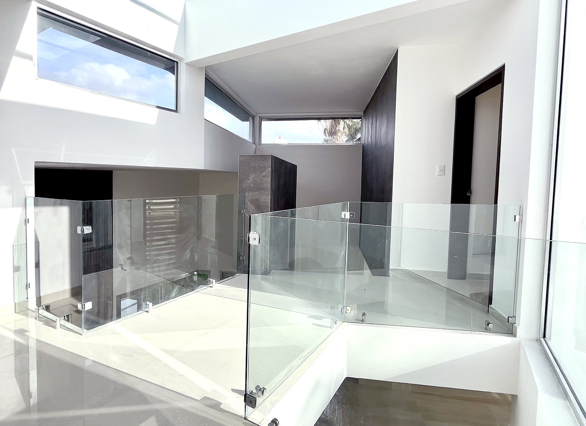 Modern interior with glass railings and sunlight streaming through windows.