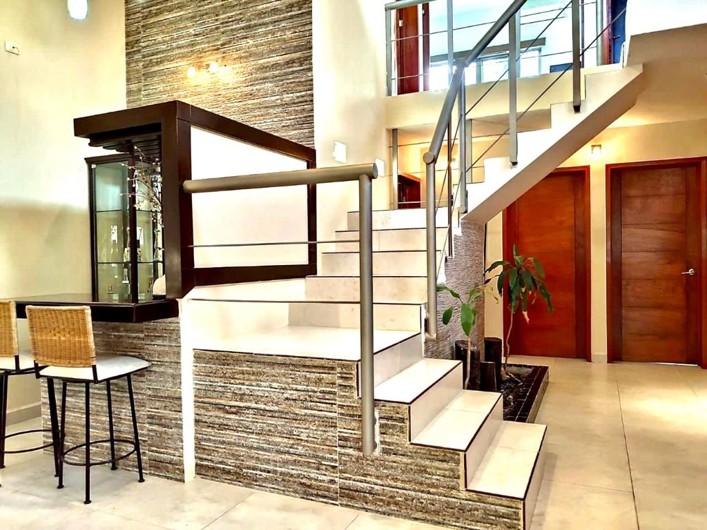 Modern interior with a staircase, wooden doors, bar area with stools, and indoor plants