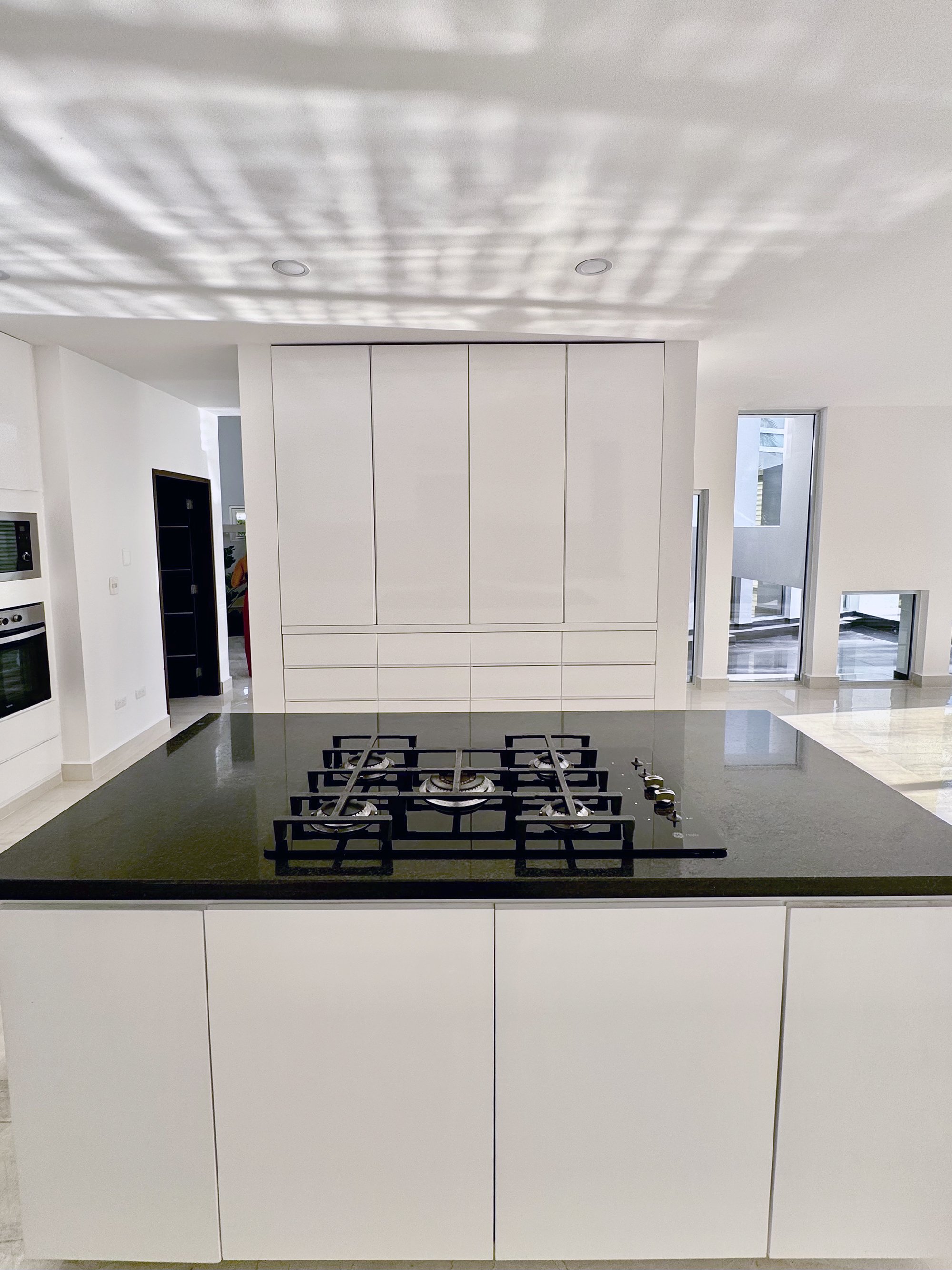 Modern kitchen with white cabinets and an island featuring a black countertop and gas stove.