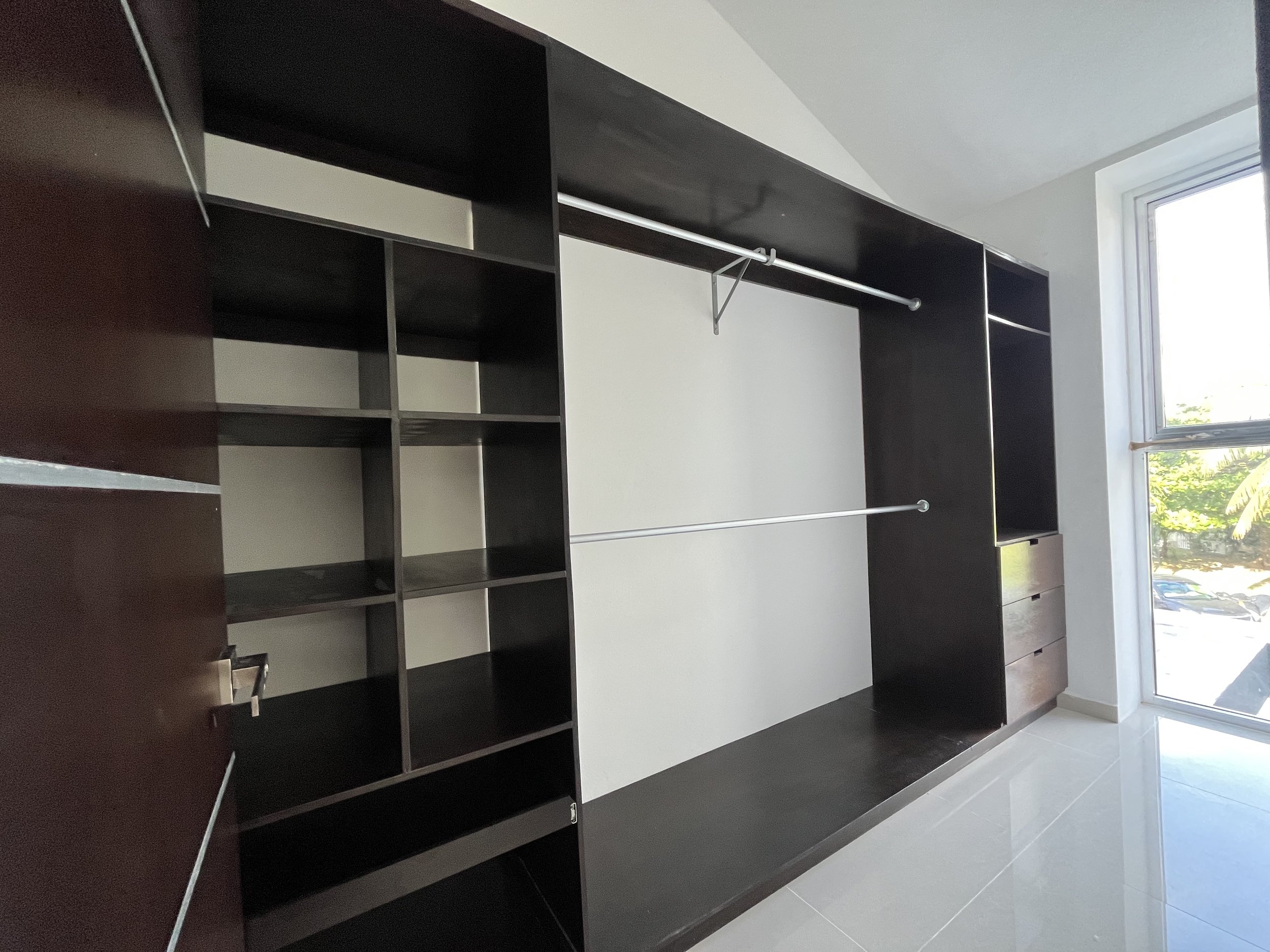 Empty walk-in closet with dark wood shelves, drawers, and metal hanging rods