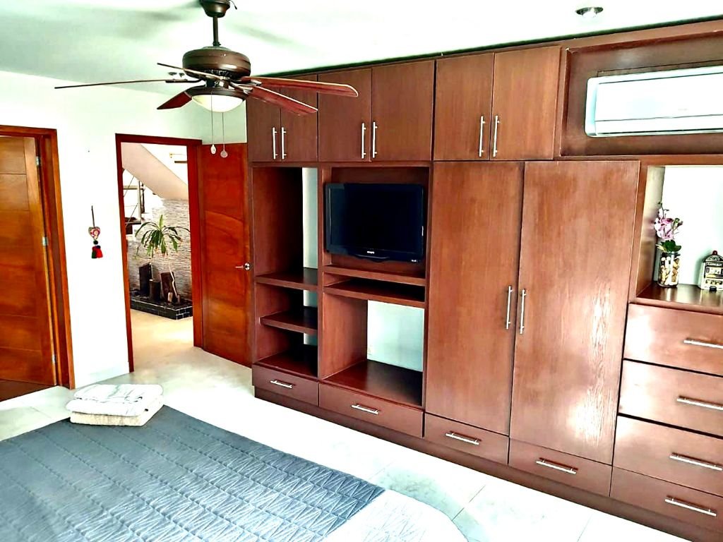 Bedroom with wooden wardrobe, ceiling fan, and TV
