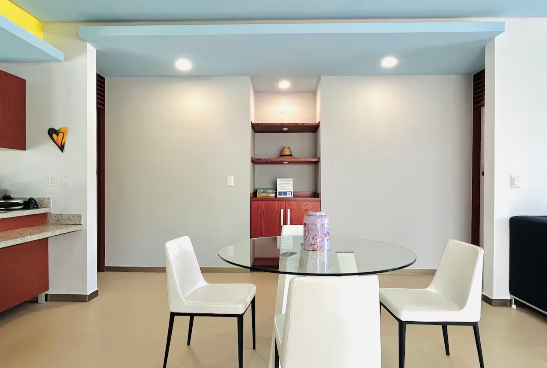 Modern dining room with a glass table, white chairs, and decorative shelves.