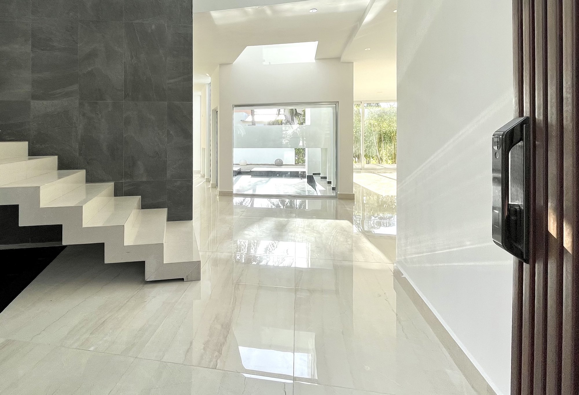 Modern interior with marble flooring, open staircase, glass windows, and natural light.