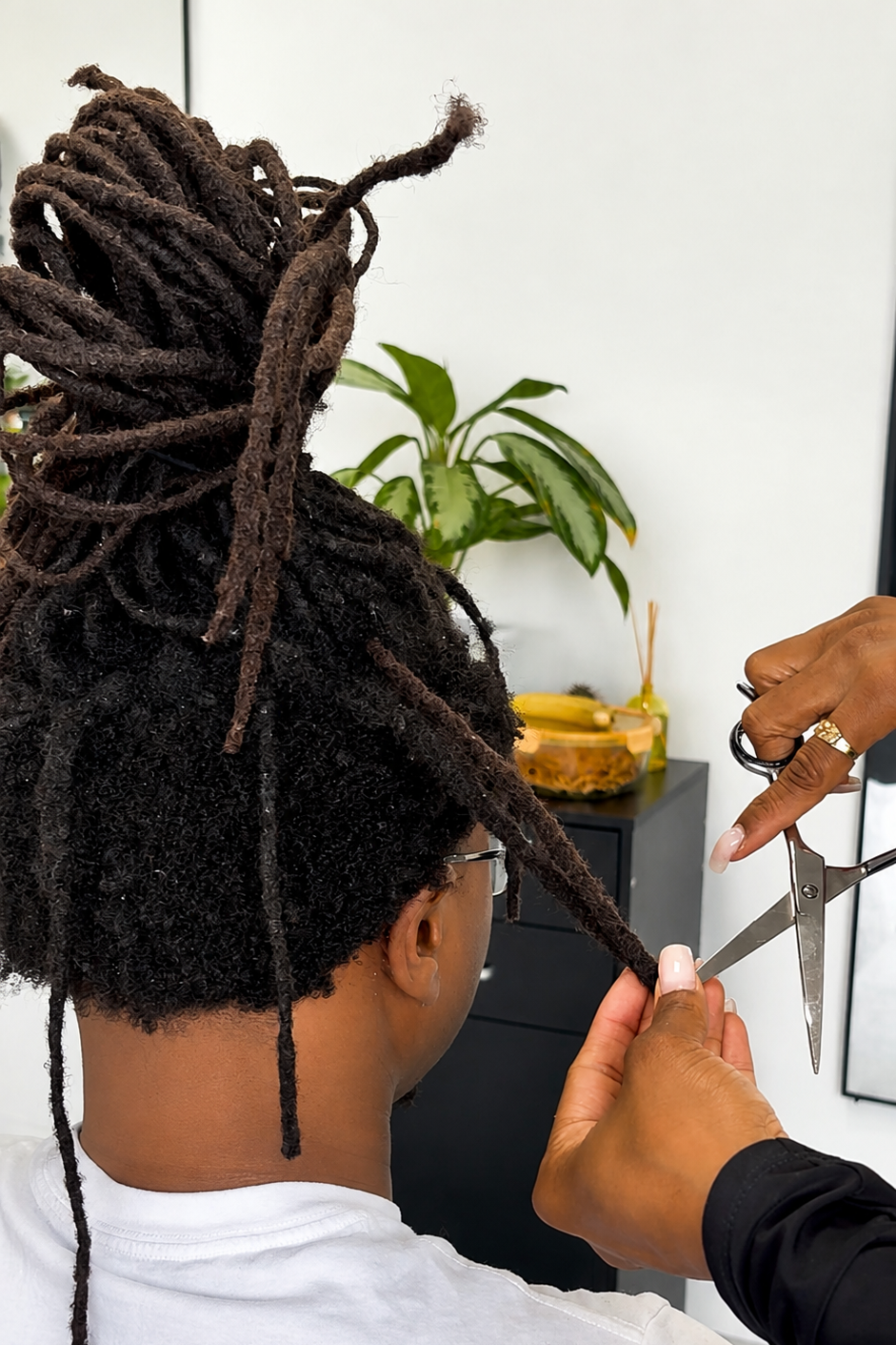 Client’s locs are cut in half and reattached to the sides and back of his head.