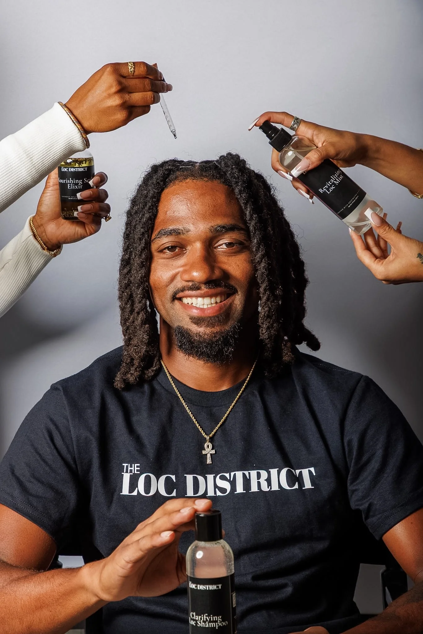 Person with dreadlocks smiling, wearing a black T-shirt with