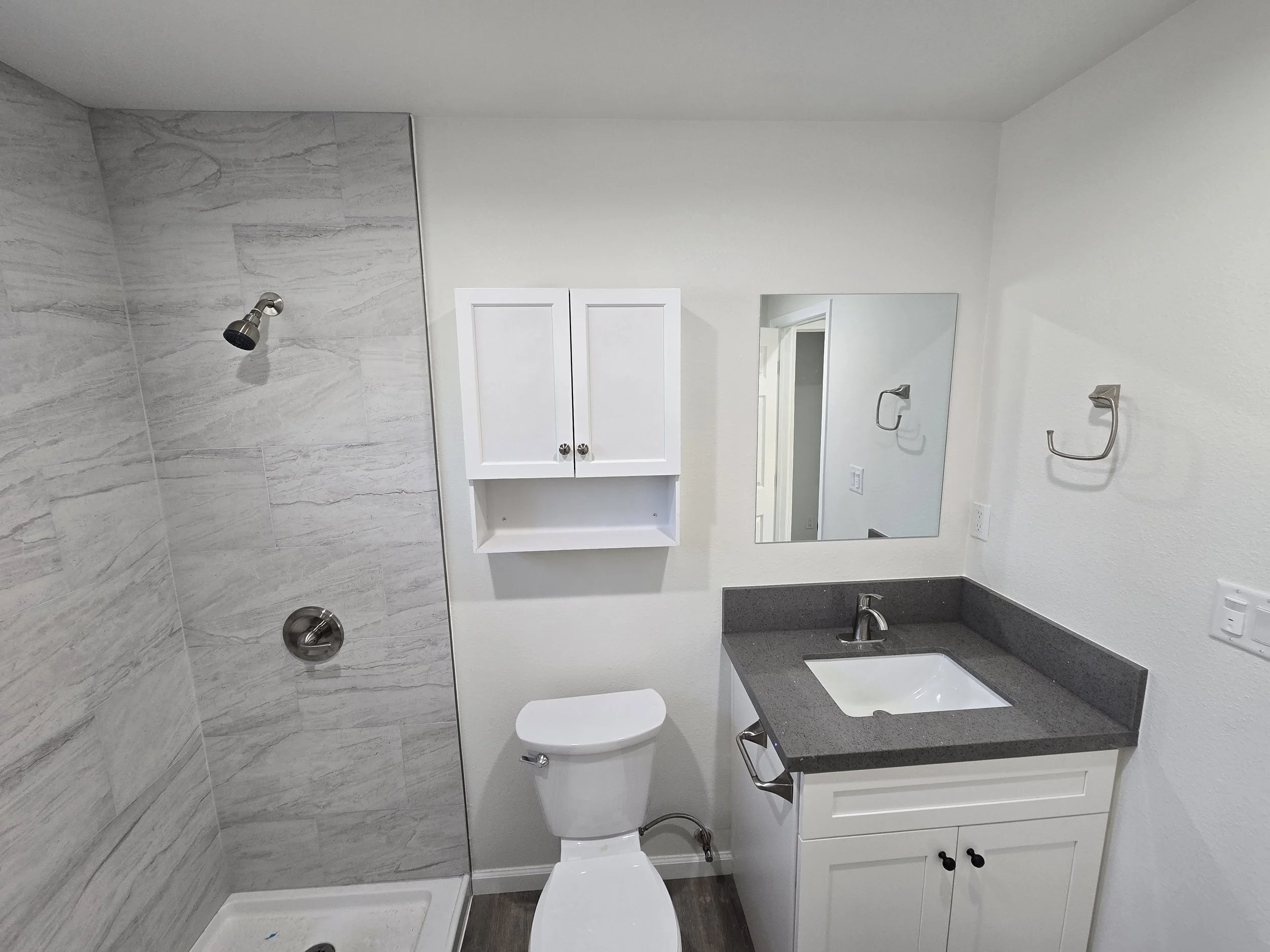 ADU bathroom with porcelain tile in the shower along with a vanity that has a quartz counterop