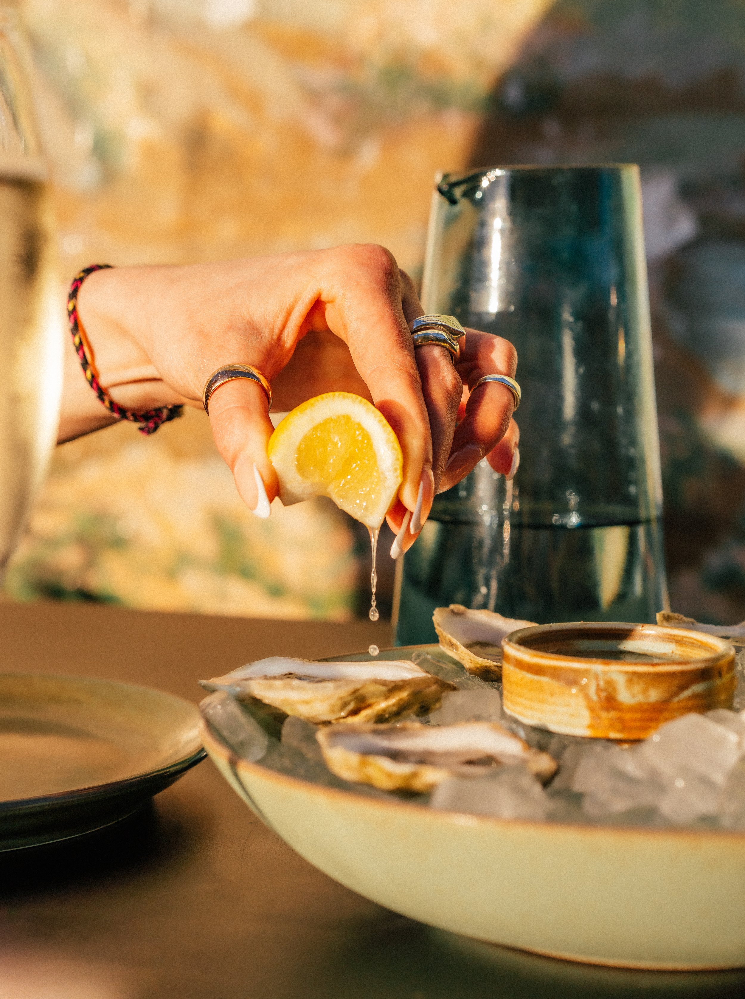 A hand squeezing a lime ove a plate of oyters