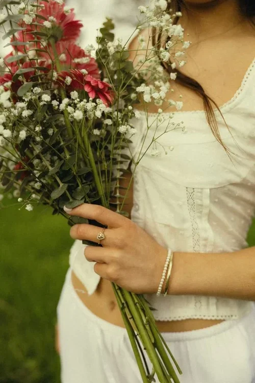 Person holding a bouquet of fresh wildflowers outdoors, symbolizing self-worth, confidence, emotional healing, and self-trust therapy support.