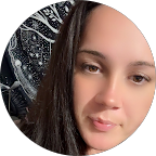 Close-up of a young woman's face with light makeup and a slight smile, against a dark background.