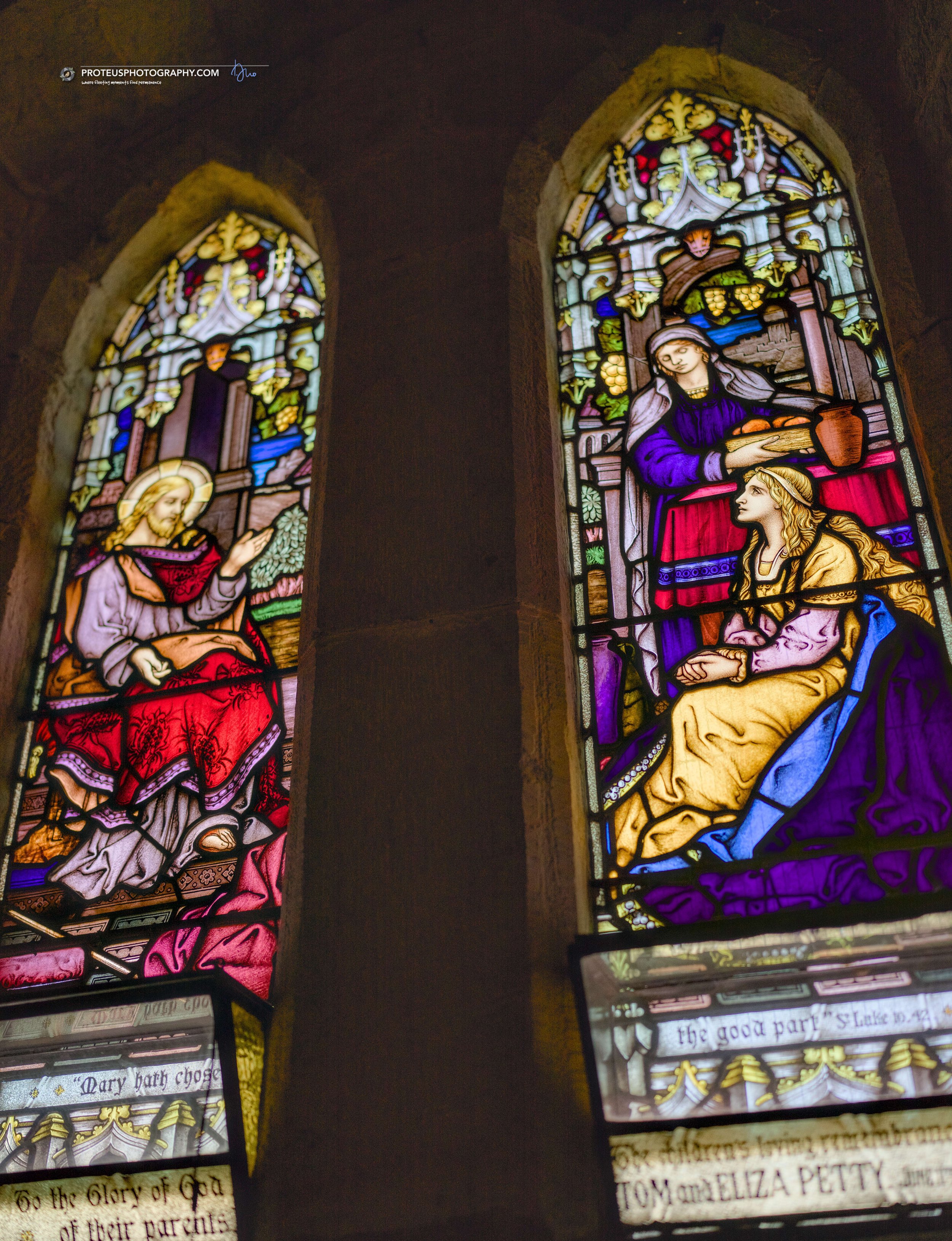 Two stained glass windows depicting religious scenes inside a church, with images of Mary and Joseph, and various biblical references and texts at the bottom.