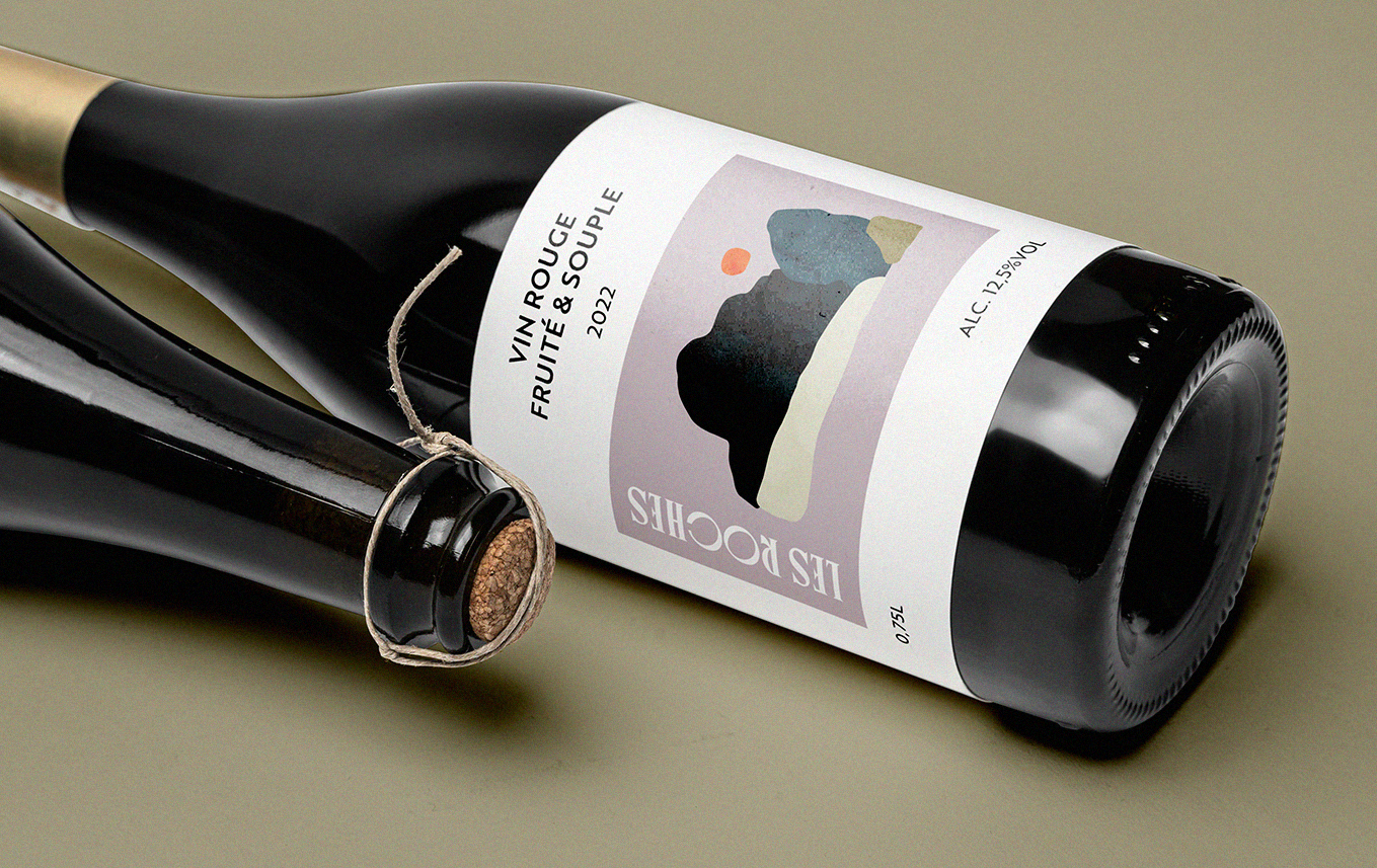 Une bouteille de vin rouge avec une étiquette moderne mentionnant 'VIN ROUGE FRUITÉ & SOUPLE 2022' et un autre flacon de vin sans étiquette visible.