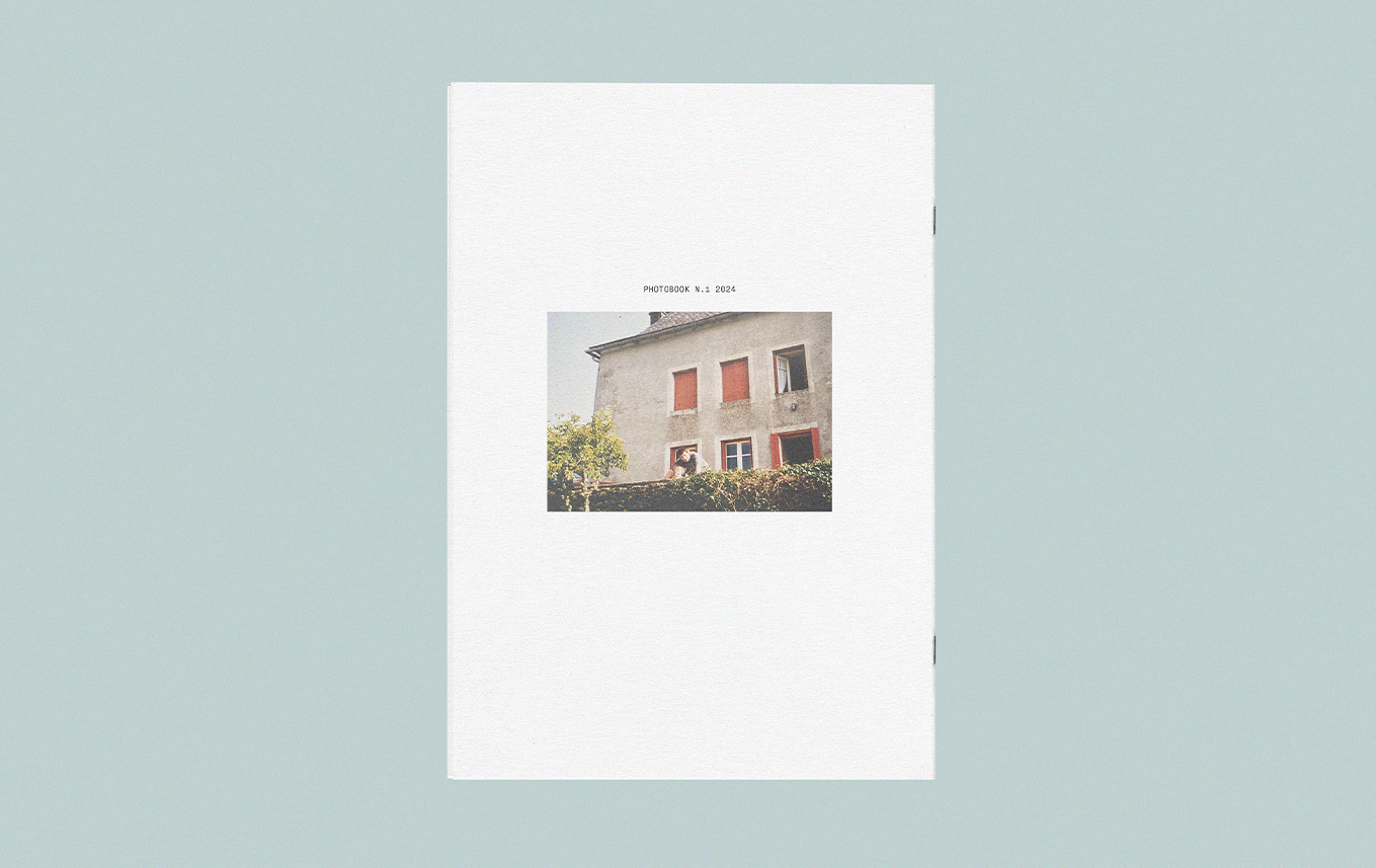 Page de cahier avec une photo d'une maison, texte "Photobook N. 1 2024"