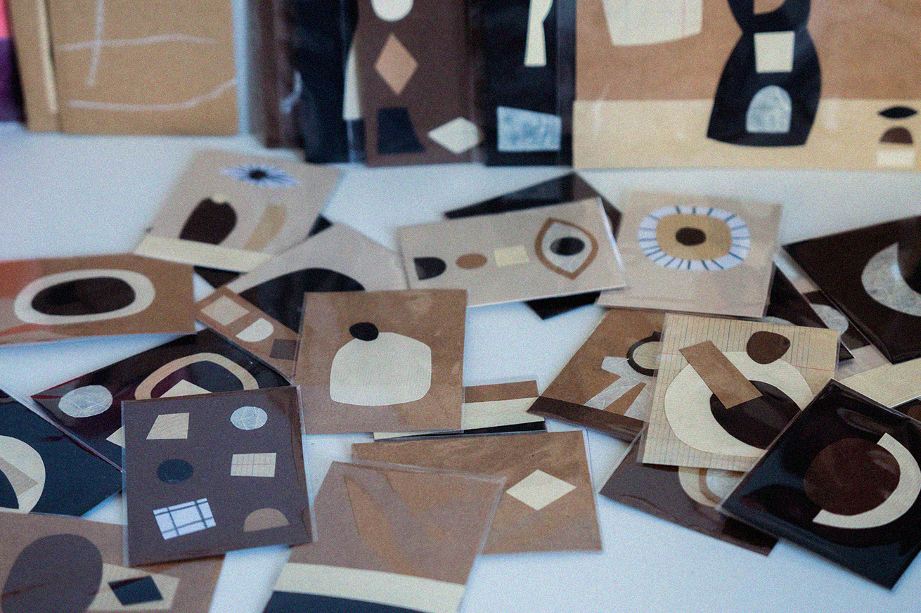 Une table recouverte de cartes à jouer avec des motifs géométriques abstraits dans des tons de brun, beige, noir et blanc.