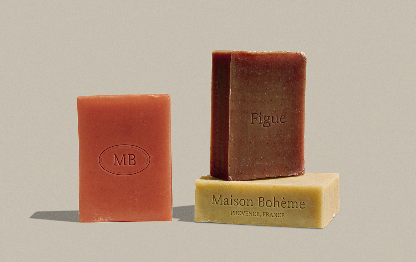 Trois barres de savon de différentes couleurs et tailles, avec des inscriptions mepotant "MB," "Figue," et "Maison Bohème Provence, France."