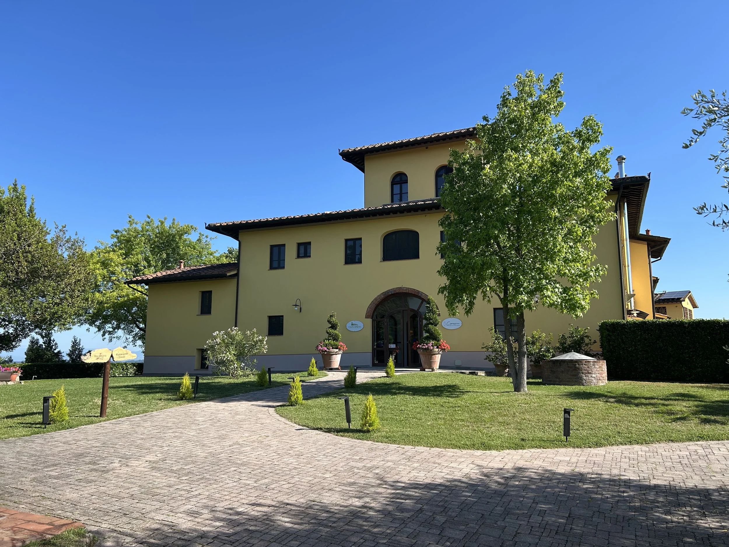 Yellow house with trees and garden under clear blue sky