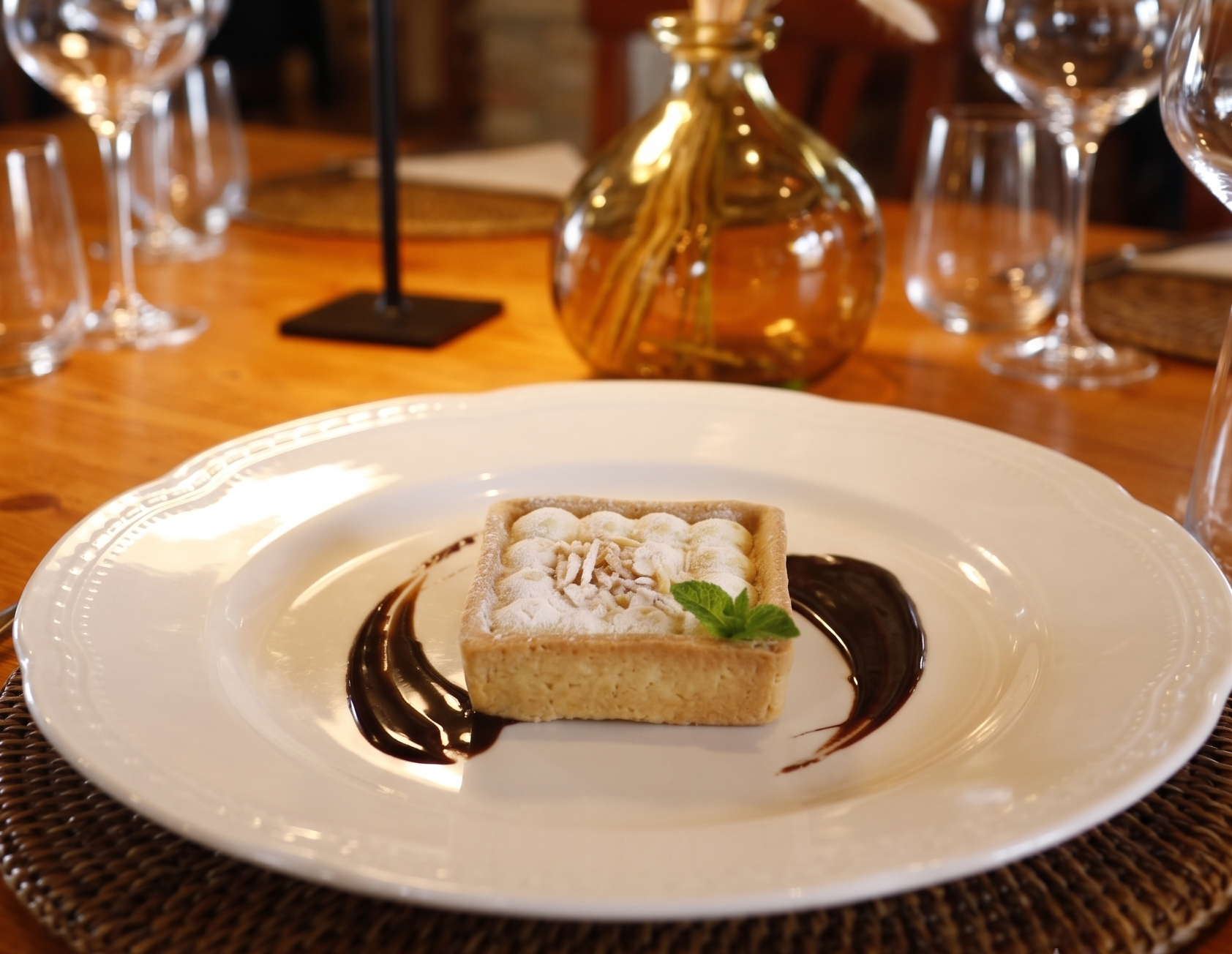 Apple tart dusted with icing sugar and served with chocolate sauce