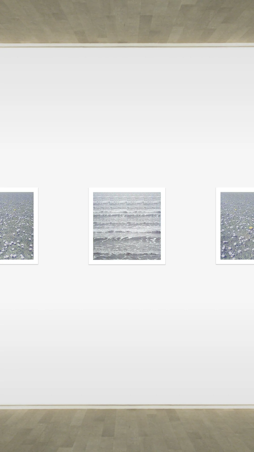 Three framed photographs of the ocean and beach hanging on a white gallery wall.