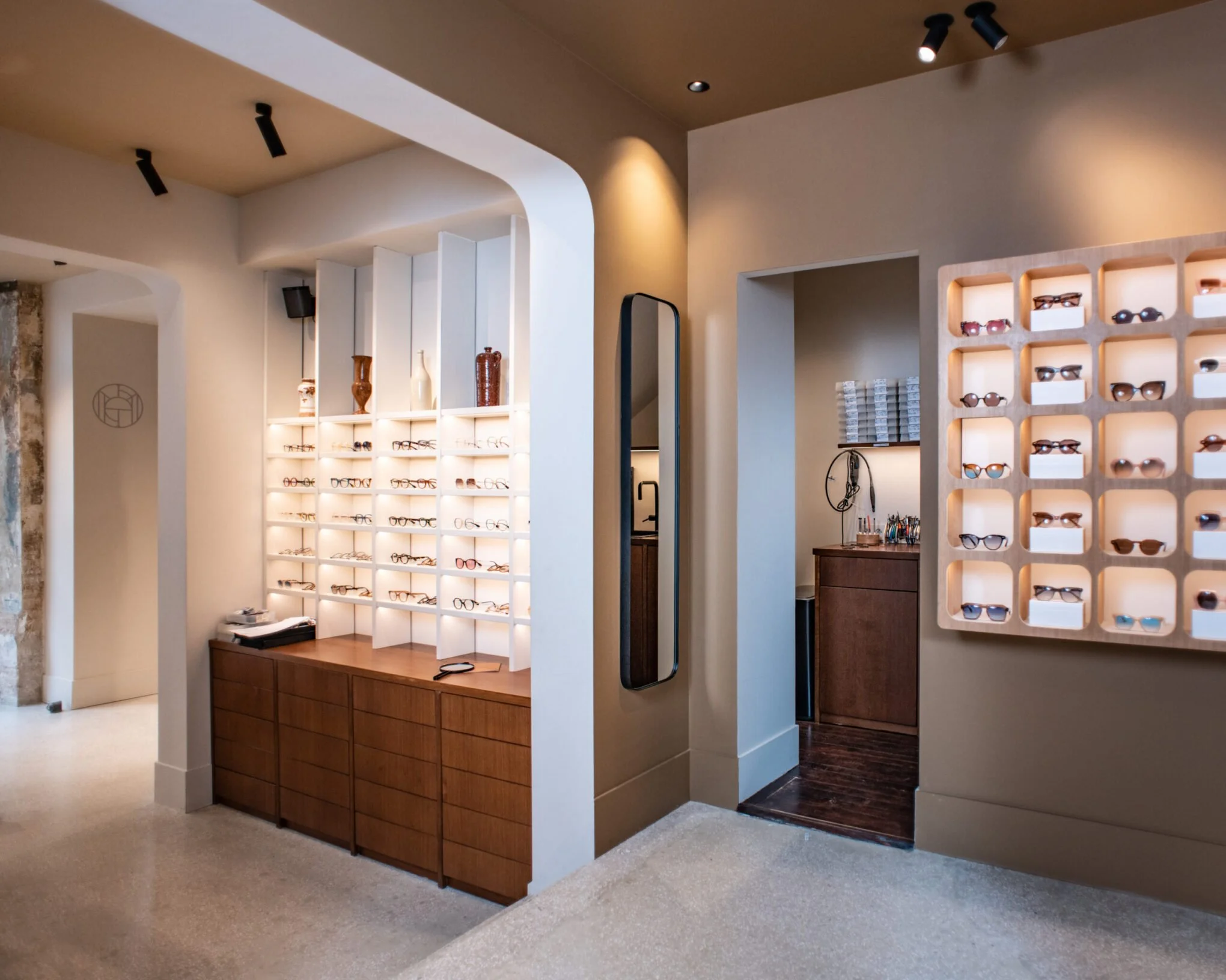 Salon optique avec étagères de lunettes et vitrine lumineuse, décor moderne et épuré.