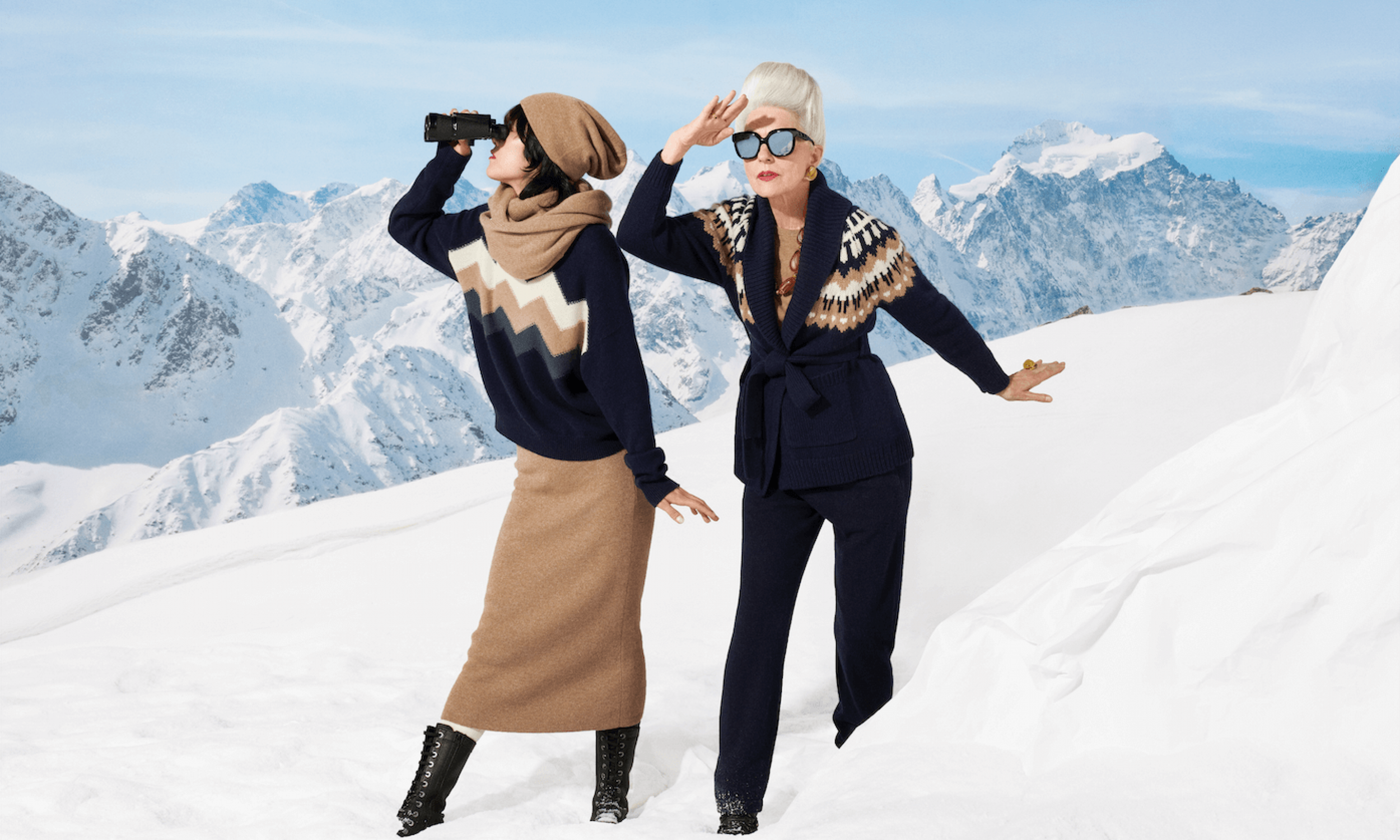 Deux femmes dans un paysage enneigé avec des montagnes en arrière-plan, portant des vêtements d'hiver élégants et regardant au loin, utilisant des monoscopes