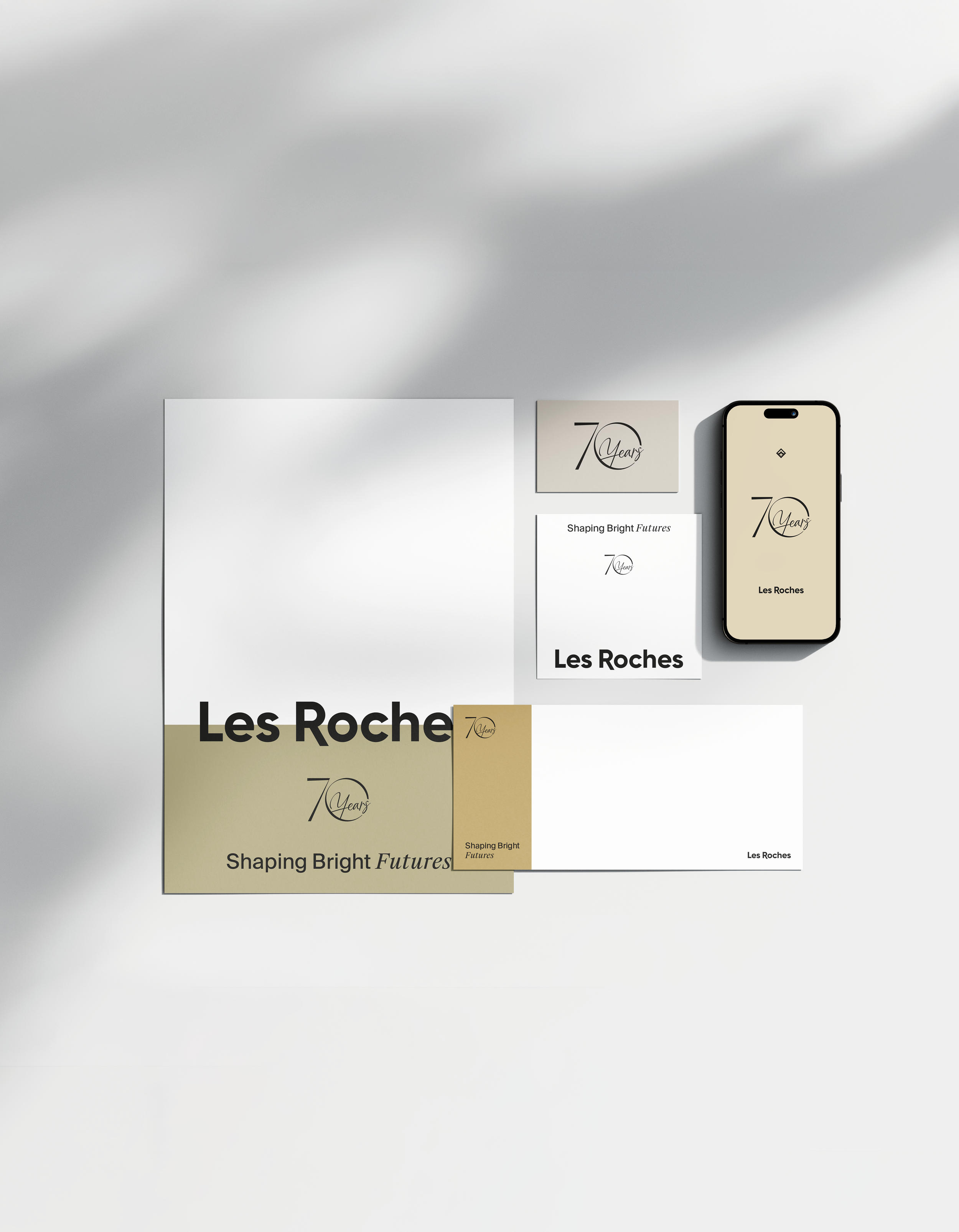 Matériel de branding pour la célébration du 70e anniversaire de Les Roches, comprenant des cartes, un smartphone et un poster avec des éléments de design et des slogans.
