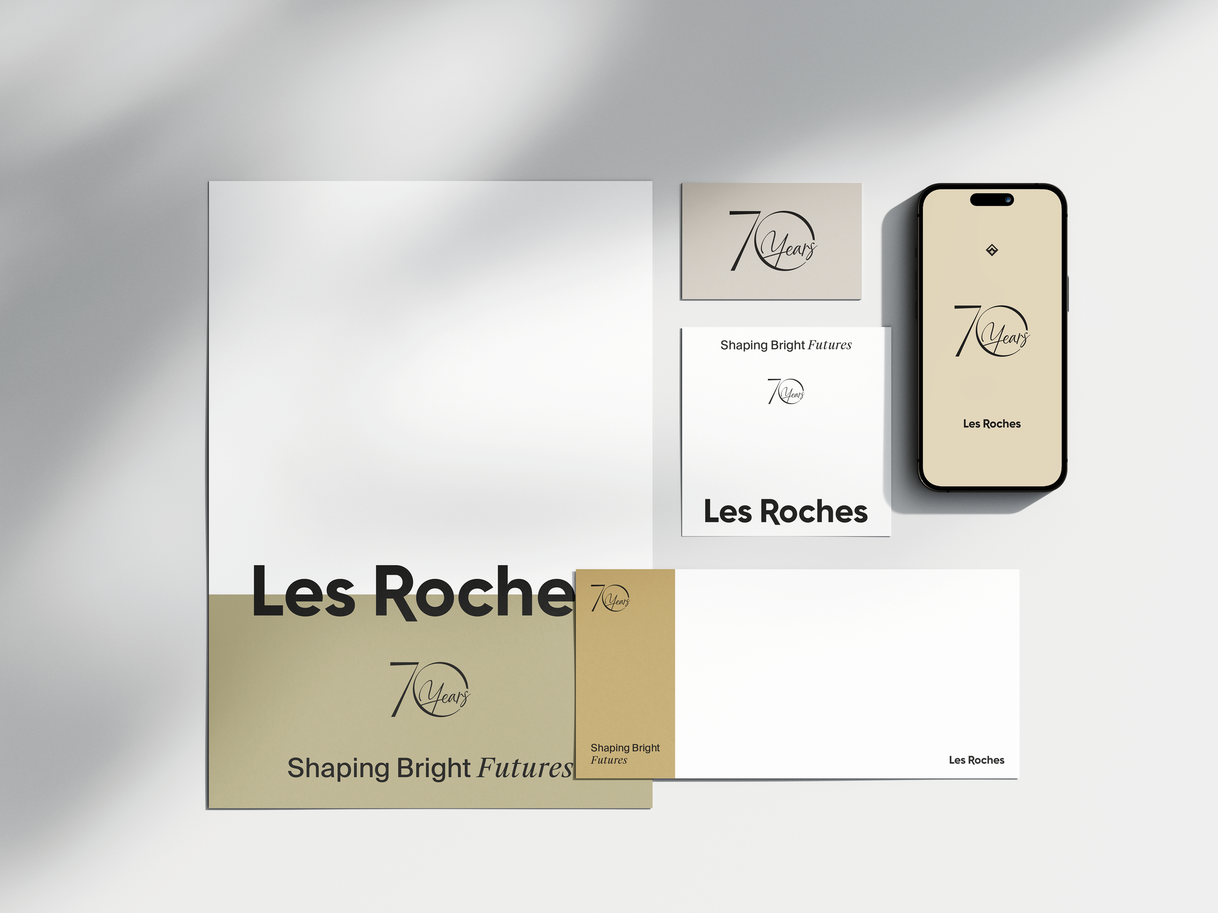 Collection de documents et d'un téléphone portable, tous portant le logo et le nom de 'Les Roches'.