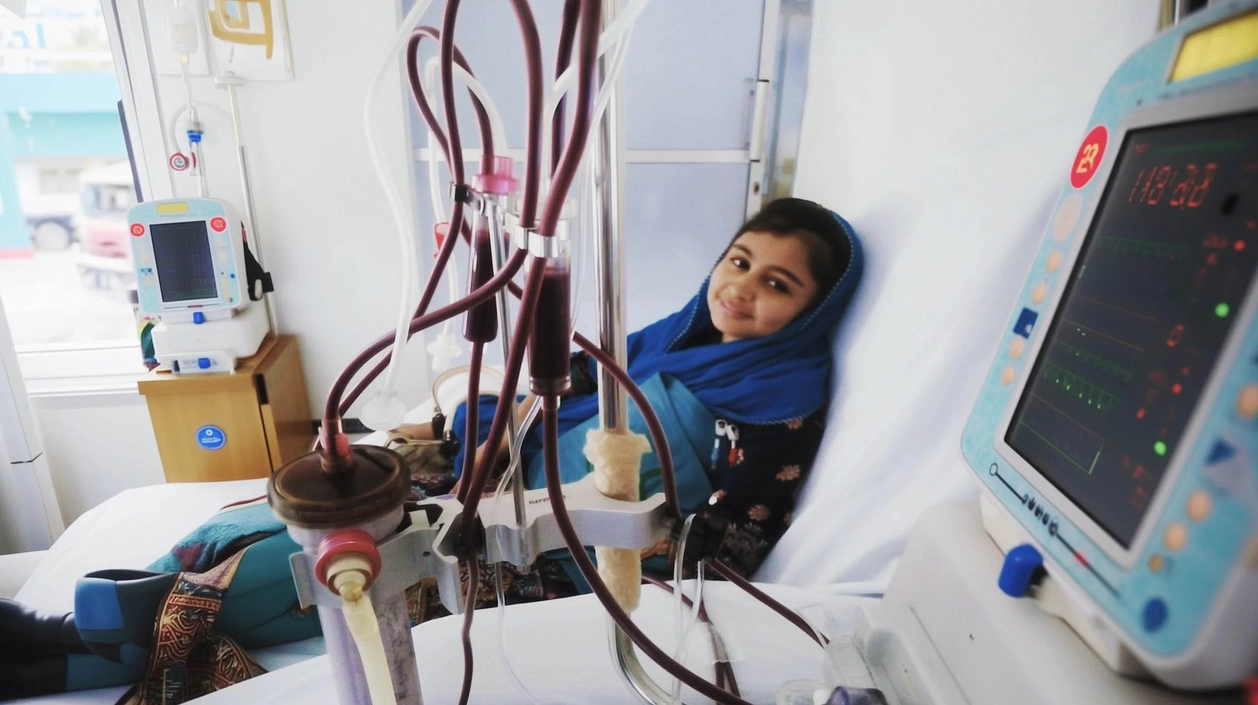 A young woman in a hospital bed receiving dialysis treatment