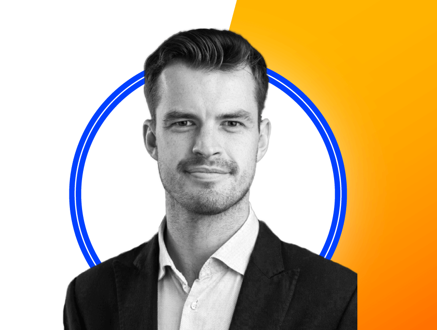 Black and white portrait of a man in a suit jacket and collared shirt, with a decorative background featuring blue rings and a gradient yellow to orange section.