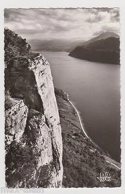 Paysage de montagnes rocheuses avec un lac au premier plan, nuages dans le ciel, en noir et blanc.