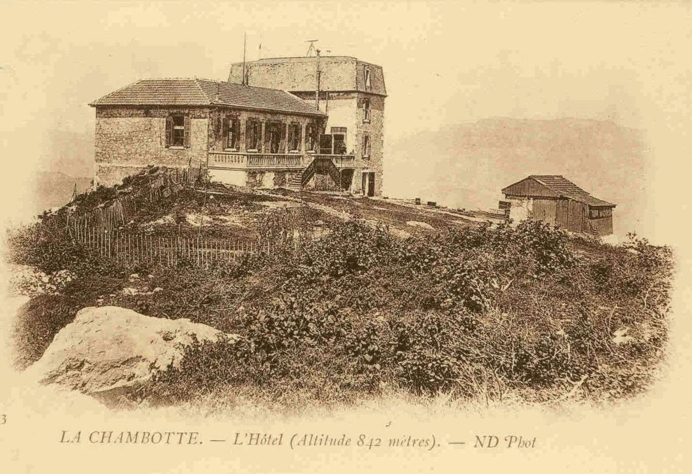 Une vieille photo d'un hôtel à La Chambotte, situé à une altitude de 842 mètres, avec des bâtiments en pierre et un environnement boisé.