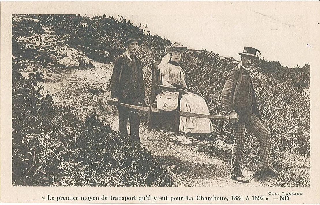 Trois personnes, deux hommes et une femme, sont sur un chemin en pleine nature. La femme est assise sur une civière portée par les deux hommes. Elle porte un bonnet et une robe ancienne. Les hommes portent des chapeaux et des vêtements caractéristiques de la fin du XIXe siècle.
