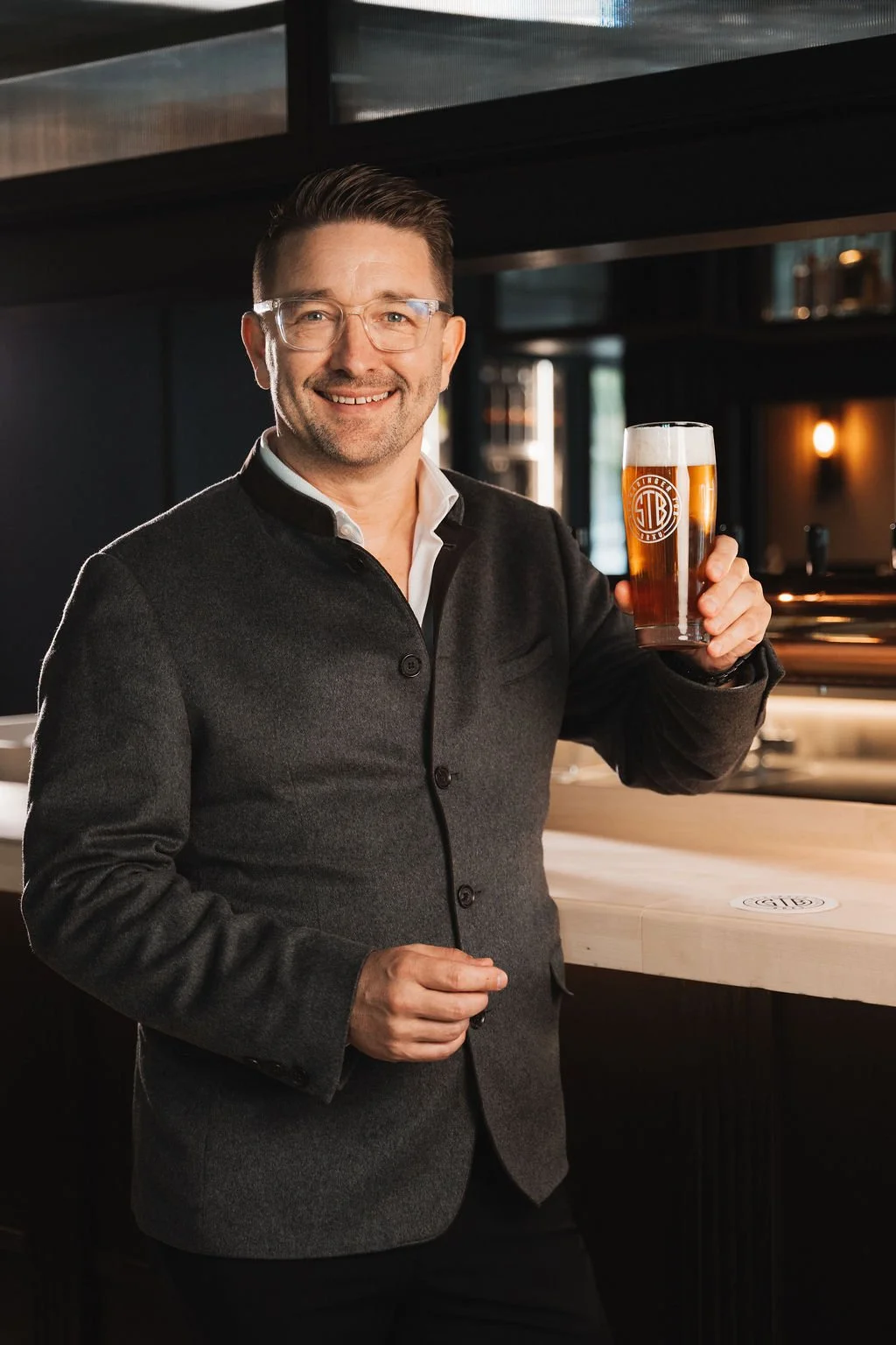 Frank Heckelmann, holding a glass of beer at Schwabinger Tor Bräu Wirtshaus.