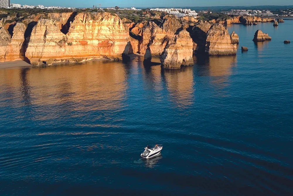Boat cruising along the Algarve cliffs