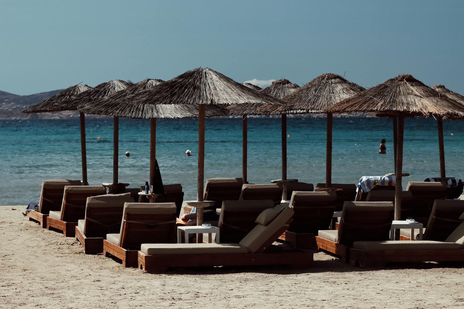 Beach with lounge chairs and thatched umbrellas, overlooking the sea.