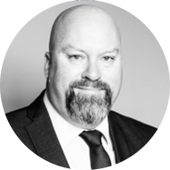 Black-and-white portrait of a smiling man with a beard and mustache, wearing a suit and tie.