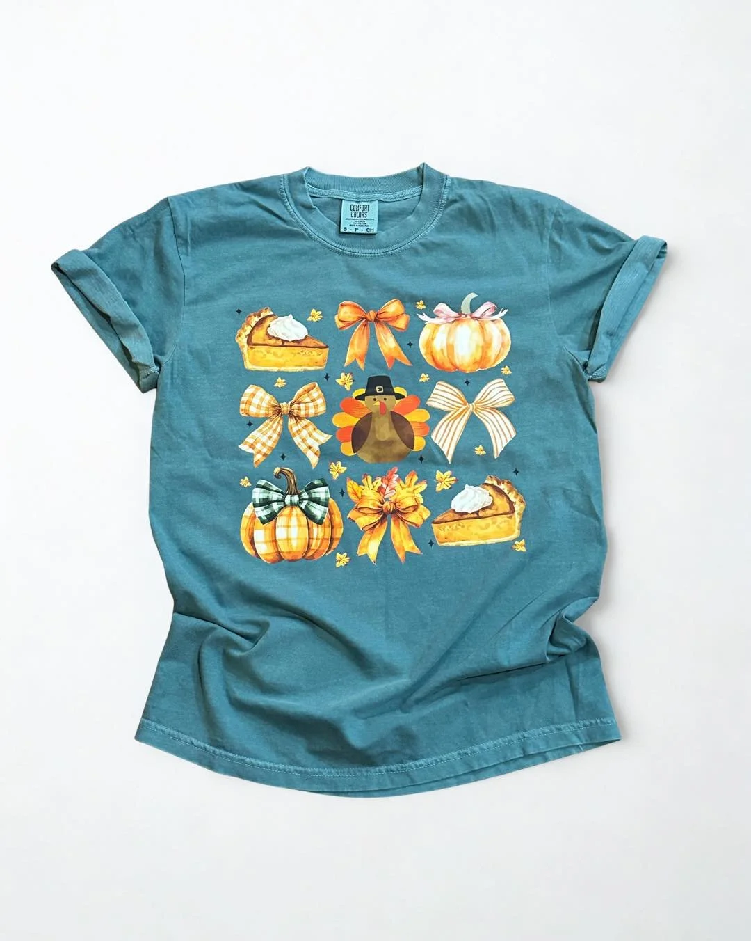 🍂 NEW ARRIVAL ALERT! 🍁
Fall has never looked this cute! This cozy emerald tee is giving all the Thanksgiving vibes &mdash; pumpkins, pie, bows, and the sweetest little turkey in the middle. Perfect for your Friendsgiving, school events, or just roc