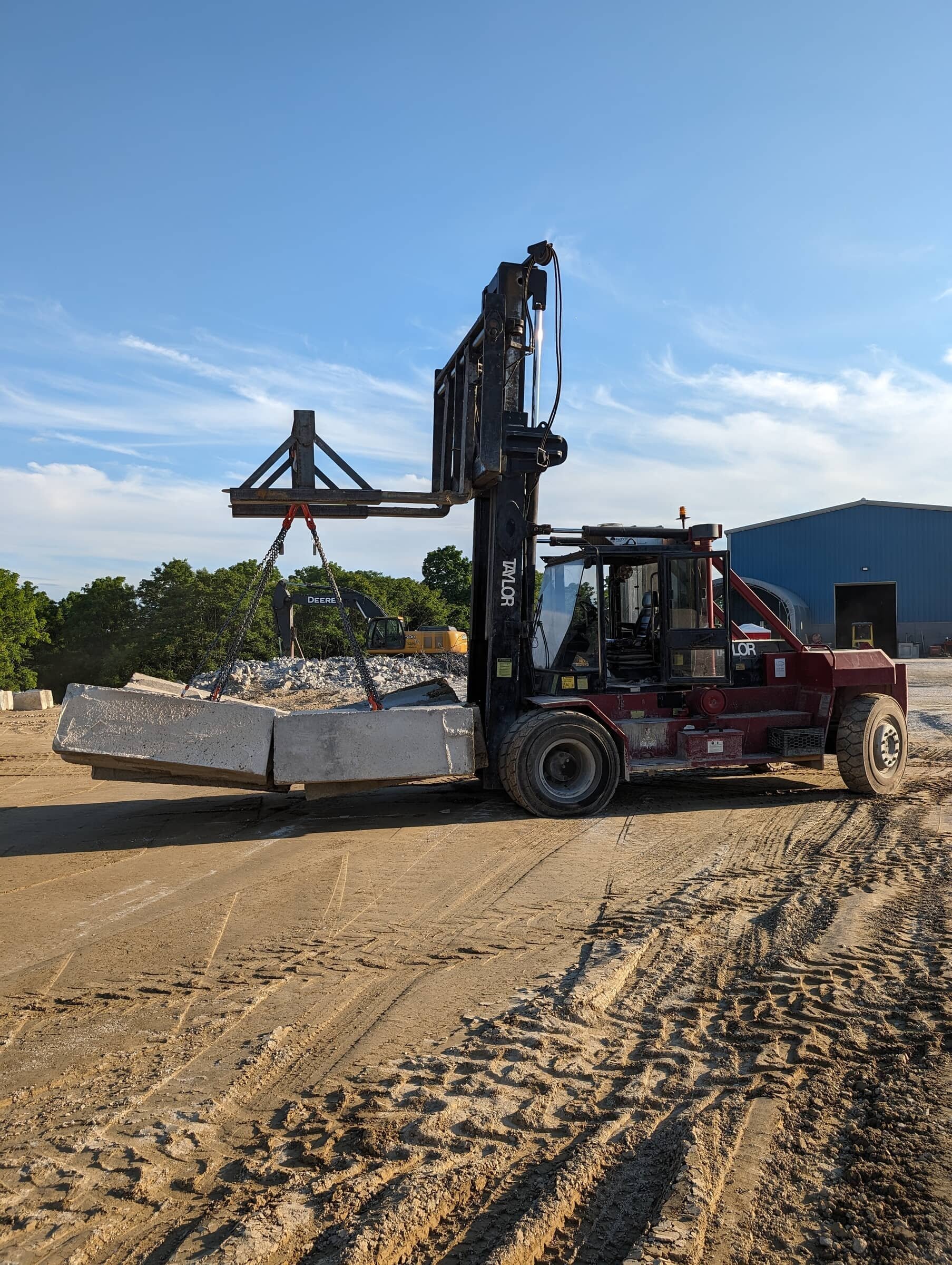 A forklift lifting large concrete blocks at a construction site during the day.